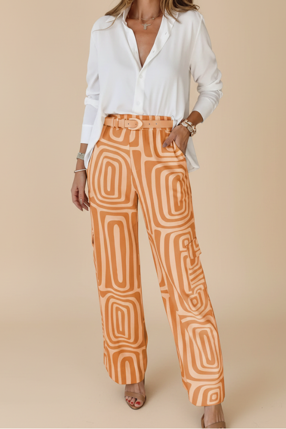 Woman wearing a white blouse and orange patterned pants on a beige background
