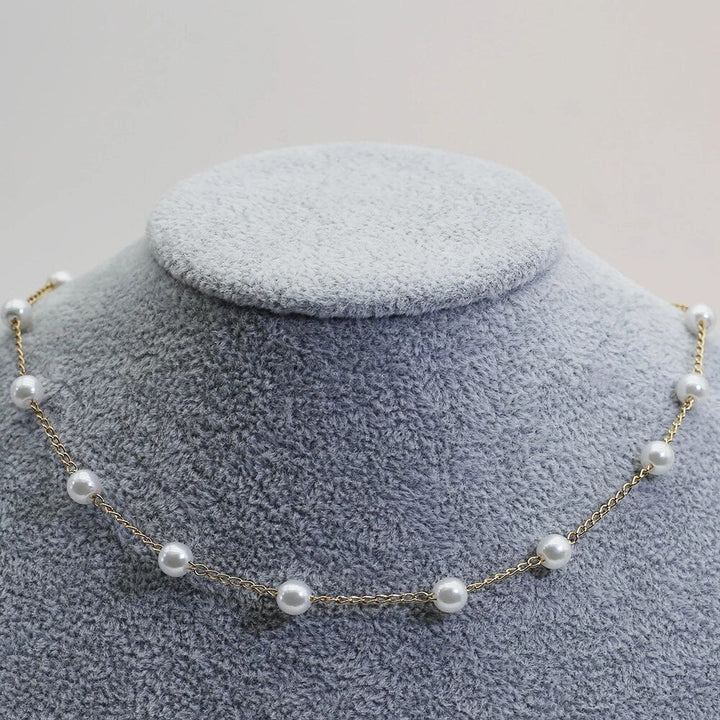 Pearl necklace on a gray velvet stand with a light gray background