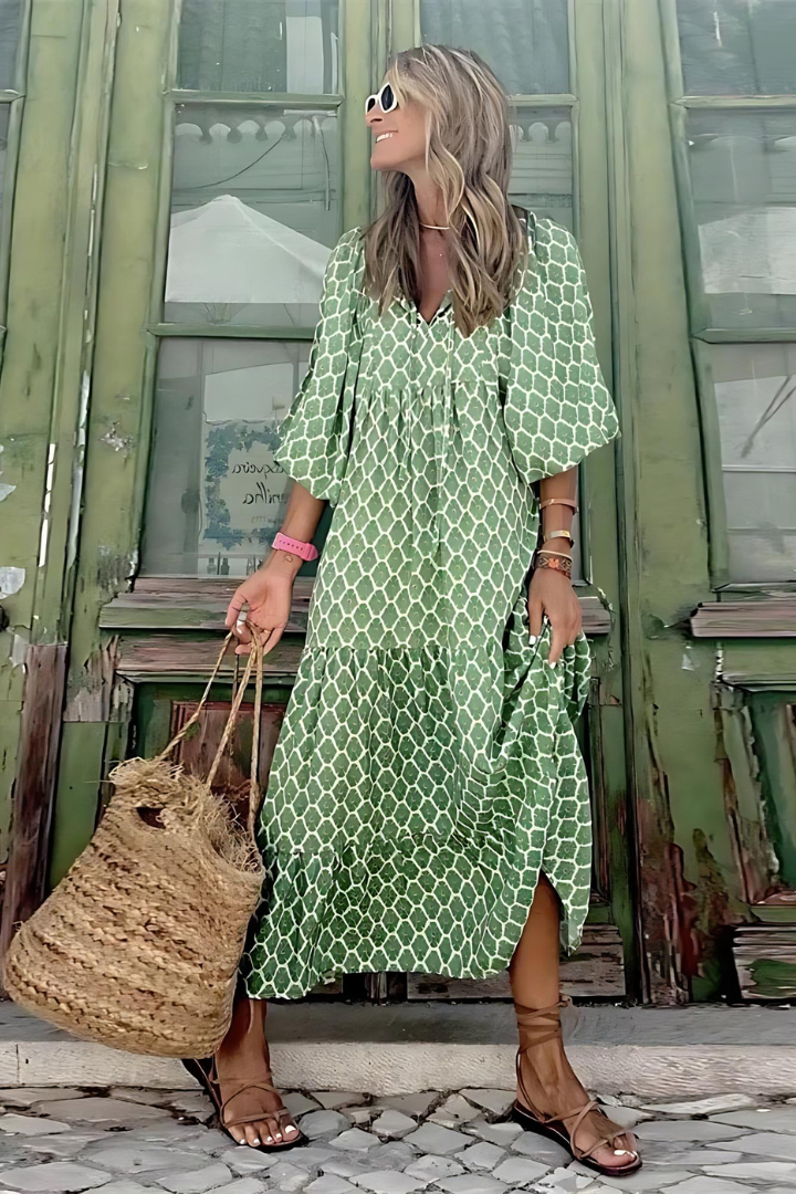 Woman in a green patterned dress standing in front of a green building.