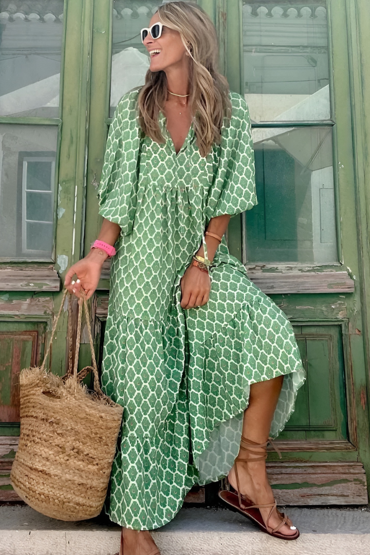 Woman in a green patterned dress standing in front of a green door.