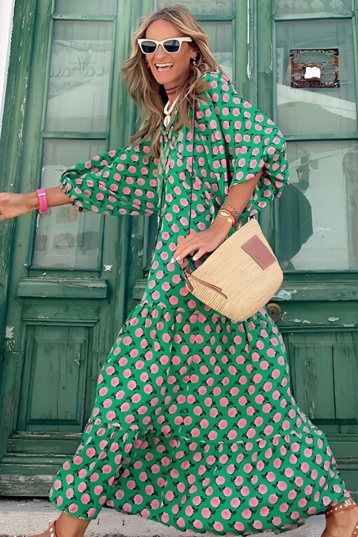Woman in a green and pink polka dot dress standing in front of a green door.