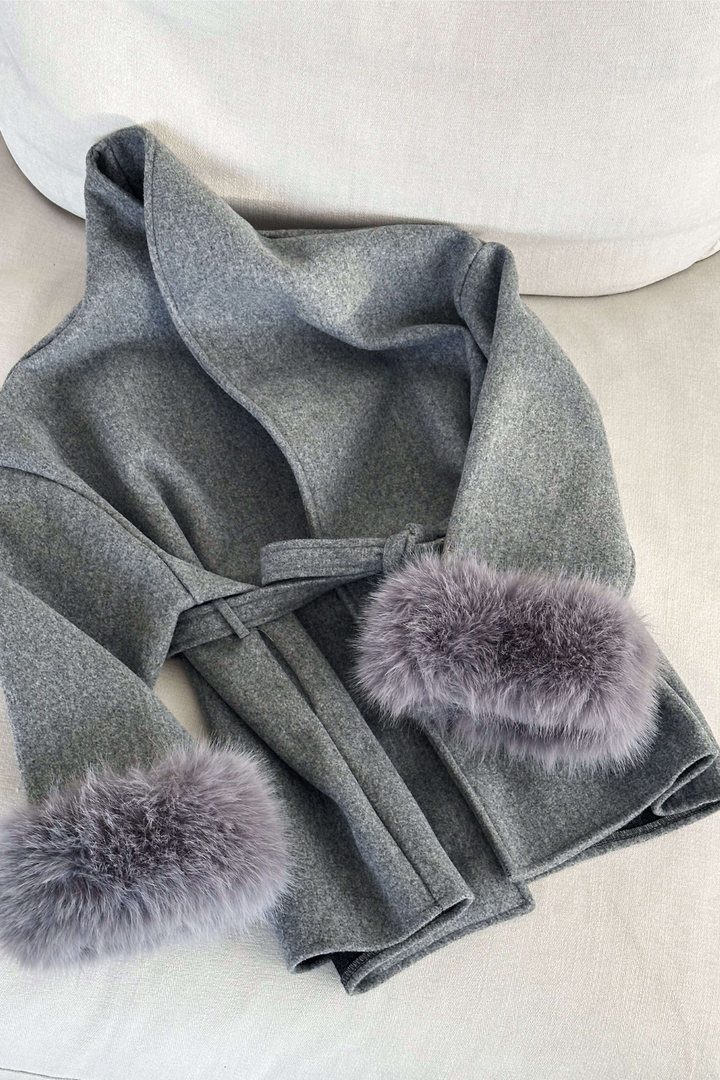 Gray coat with fur pom-poms on a light background