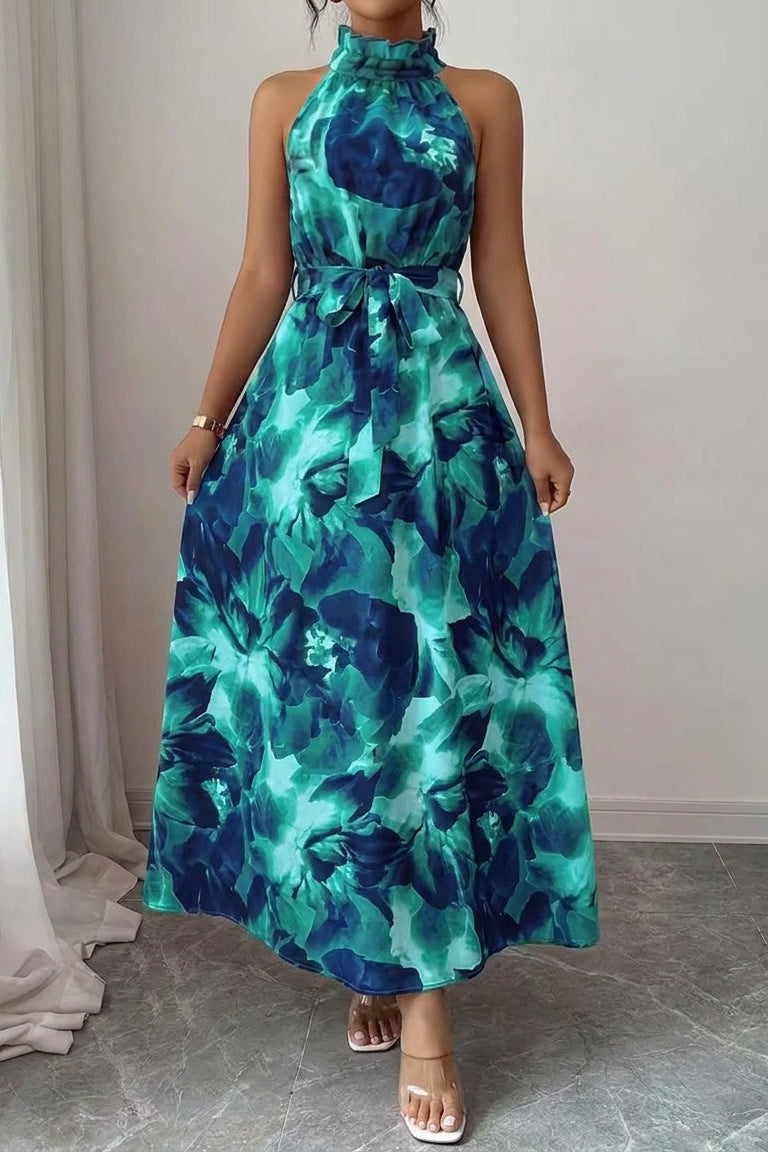 Woman wearing a green floral dress standing in a room with light-colored curtains.