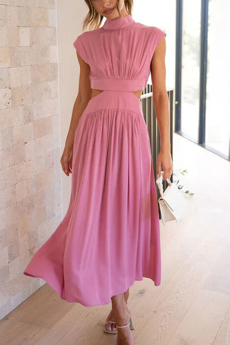 Woman wearing a pink dress standing indoors with a neutral background