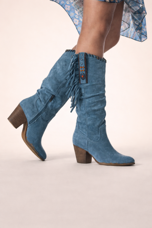 Blue fringed boots worn with a floral skirt on a light background